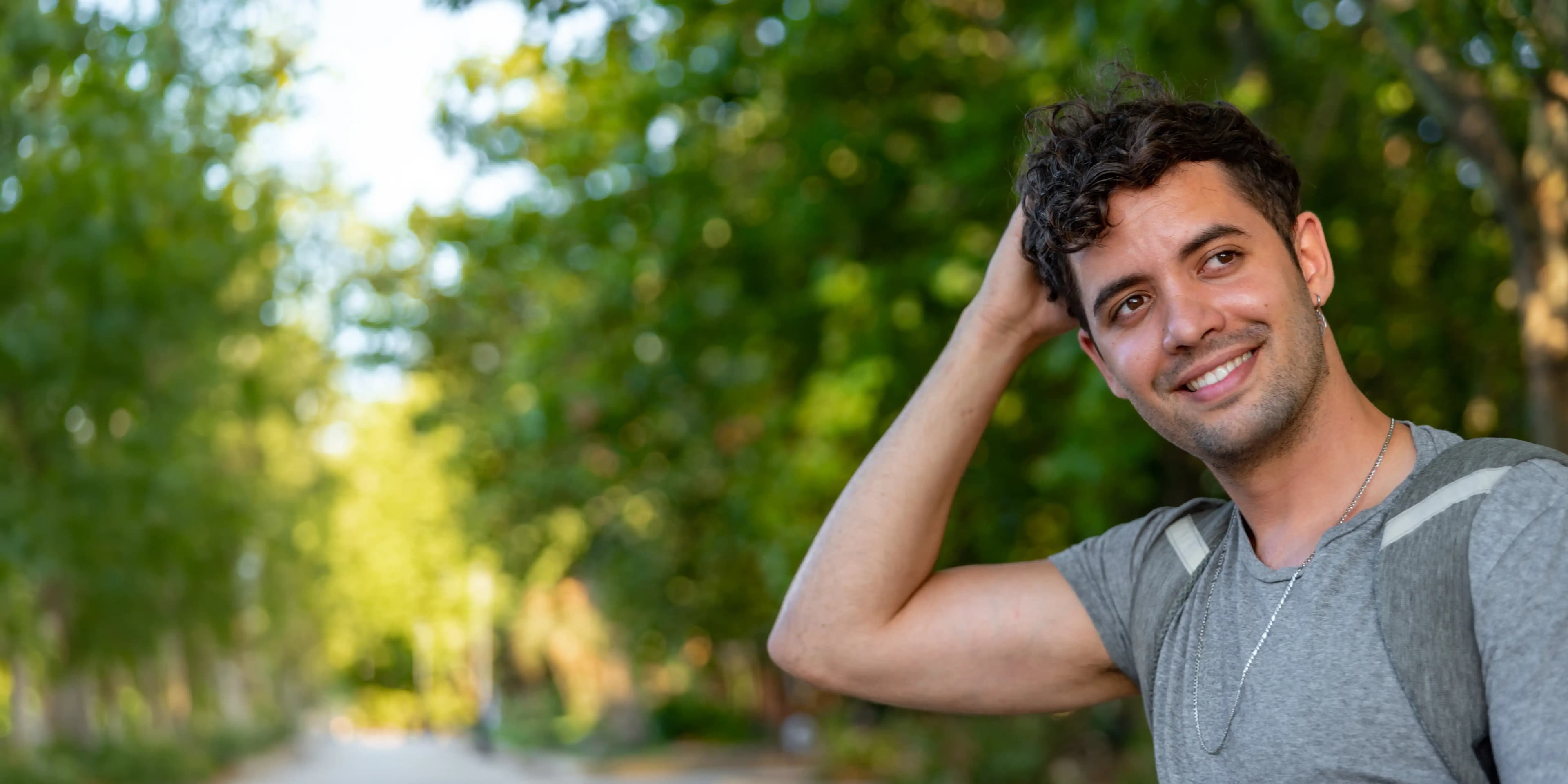 Smiling man looking away outdoors, representing confidence and satisfaction with hair loss treatment